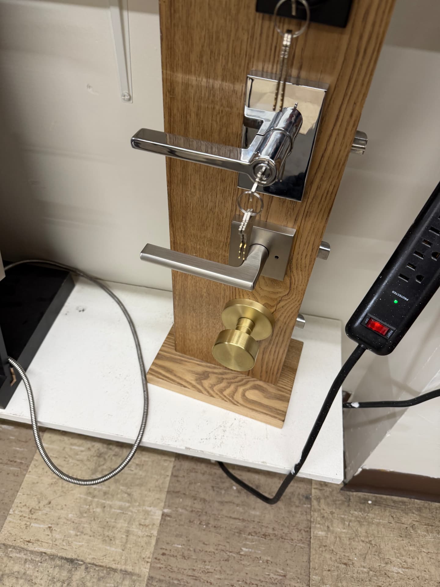 Chrome and satin nickel lever locksets with a brass knob on a display board